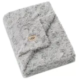 A soft, grey faux fur blanket with the UGG logo on a tan patch, featuring a textured, plush design.