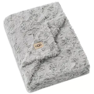 A soft, grey faux fur blanket with the UGG logo on a tan patch, featuring a textured, plush design.