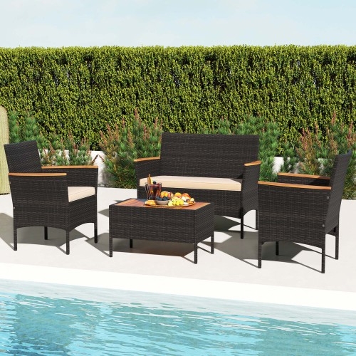 4-piece wicker patio set with two armchairs, a loveseat, and a rectangular coffee table. Features dark wicker with light-colored cushions and wooden accents on the armrests, set beside a pool with a background of tall green hedges.