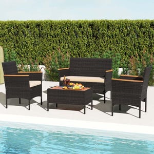 4-piece wicker patio set with two armchairs, a loveseat, and a rectangular coffee table. Features dark wicker with light-colored cushions and wooden accents on the armrests, set beside a pool with a background of tall green hedges.