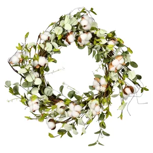 A decorative wreath featuring green leaves, twig branches, and cotton bolls.