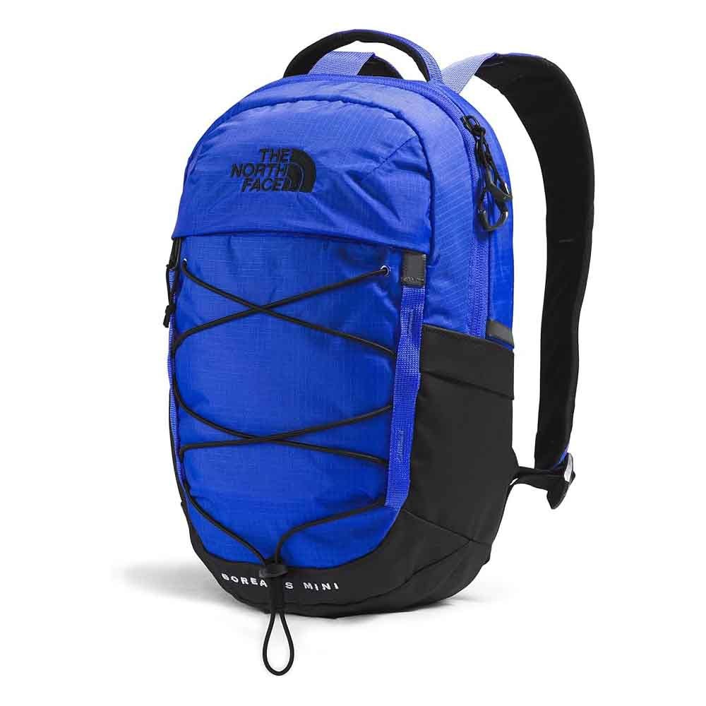 The North Face Borealis Mini Backpack is a blue and black compact backpack featuring a front bungee cord system, a zippered top, and ergonomic shoulder straps. The logo is prominently displayed at the top.