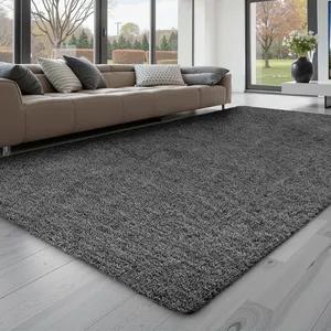 A cozy gray shag rug lies on a light wooden floor in front of a modern beige sectional sofa with various gray pillows, set in a spacious living room with large windows.