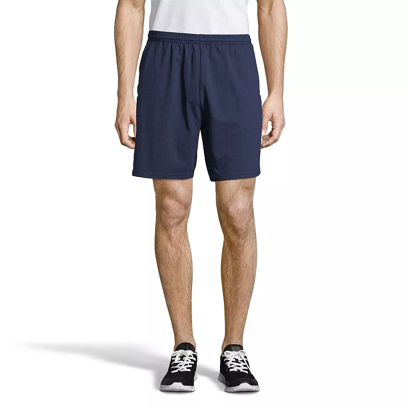 Man wearing navy athletic shorts with an elastic waistband, paired with a white shirt and black sneakers with white laces.