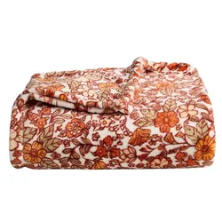 A folded, floral-patterned blanket in shades of orange, brown, and green on a white background.