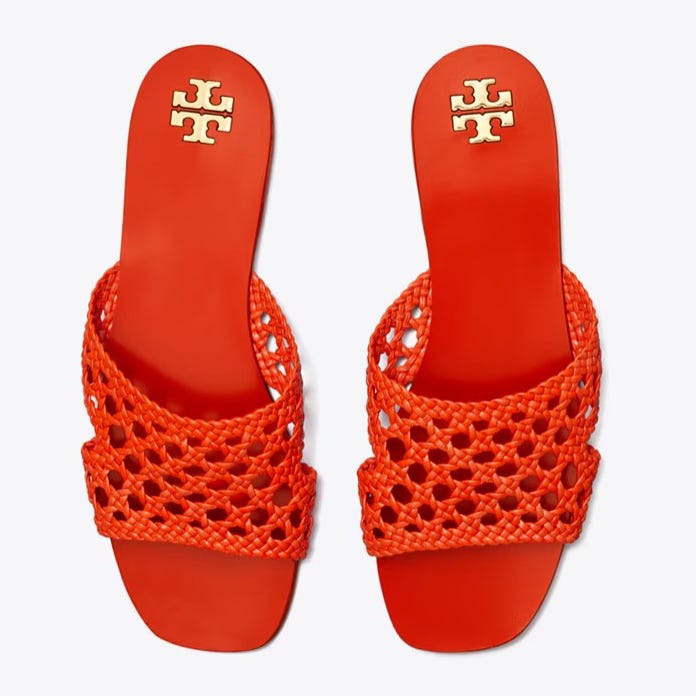 A pair of bright orange sandals with a crisscrossed, netted design on the upper part and a flat sole.