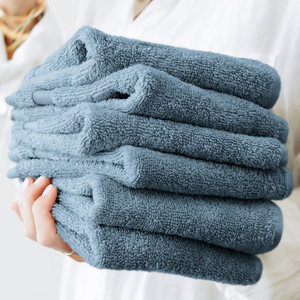 A set of six ultra-soft cotton washcloths in a muted blue color, neatly stacked. The texture appears plush and absorbent, suitable for gentle use in personal care or cleaning.