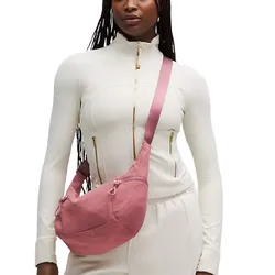 A person wears a pink crossbody bag paired with a white zippered jacket and matching pants.