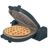 A waffle maker with a round, sectioned waffle inside, featuring a non-stick cooking surface and a dark blue exterior.