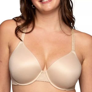 A woman is wearing a nude-colored bra with smooth, seamless cups and adjustable straps, suitable for everyday use.