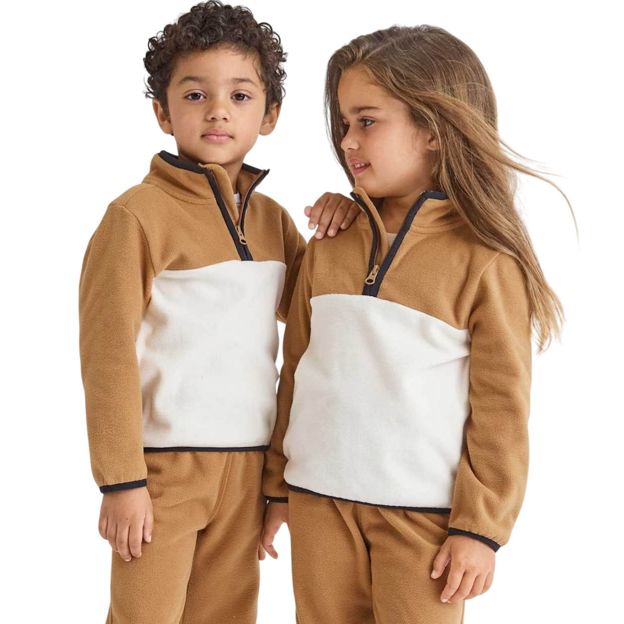 Two children wearing matching brown and white fleece outfits with half-zip collars.
