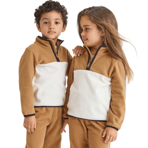 Two children wearing matching brown and white fleece outfits with half-zip collars.