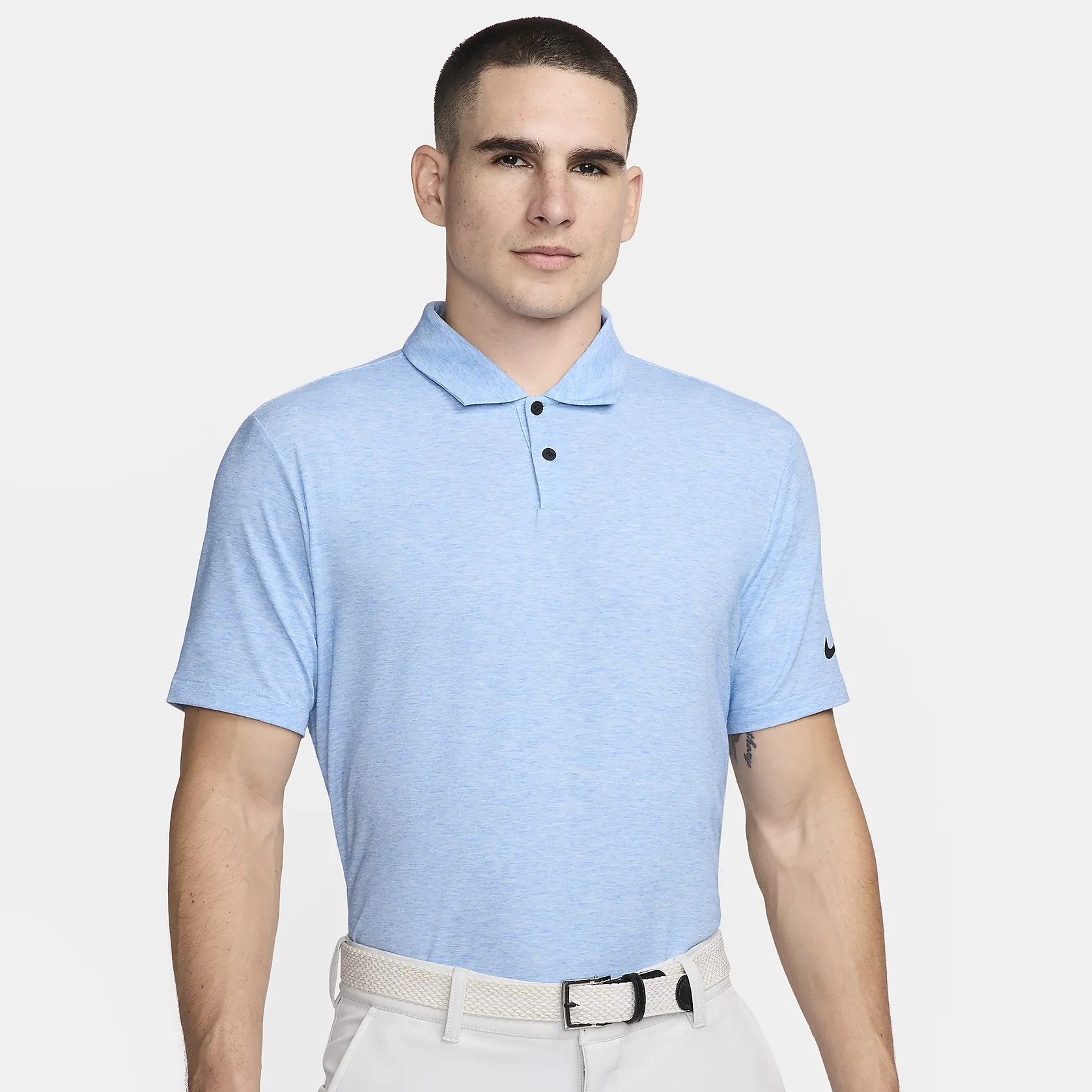 A man wearing a light blue polo shirt and a white belt.