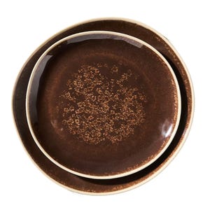 Two brown ceramic plates with a textured pattern and slightly curved edges, one smaller plate nested inside a larger one.