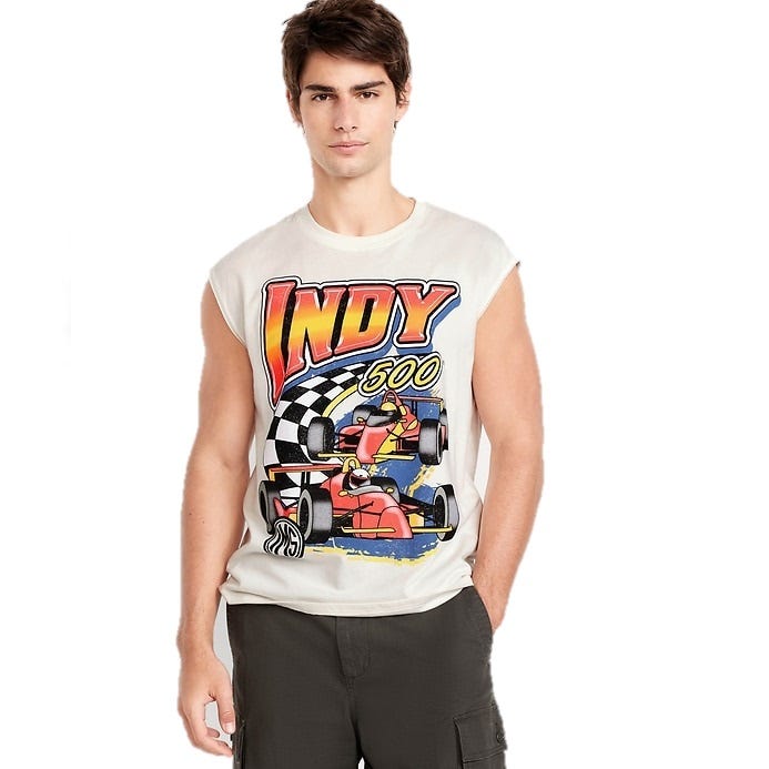 A young man wears a sleeveless white T-shirt with an \“INDY 500\“ graphic featuring racing cars and a checkered flag. He pairs it with dark cargo shorts.