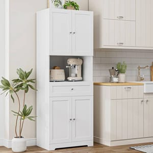 A tall white kitchen pantry with upper and lower cabinets, a small drawer in the middle, features an open shelf holding a cream-colored espresso machine and toaster, complemented by a potted plant on top.
