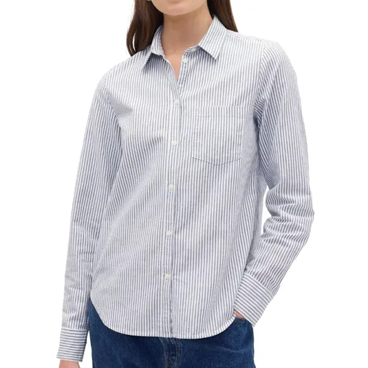 A woman is wearing a long-sleeve, striped button-up shirt with a collar and a chest pocket, paired with blue jeans.