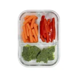 A glass container with three compartments holds baby carrots, sliced red bell peppers, and broccoli florets.