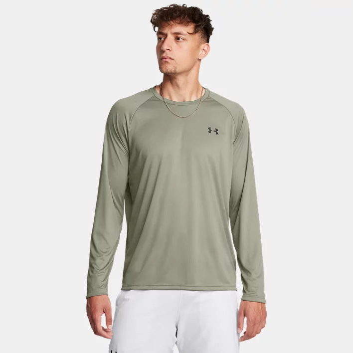 A man is wearing a long-sleeved olive green athletic shirt with a small black logo on the chest.