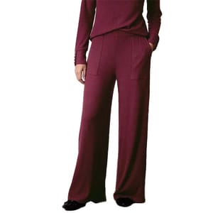 A person is wearing a burgundy set featuring a long-sleeved top and high-waisted, wide-leg pants, paired with black shoes.