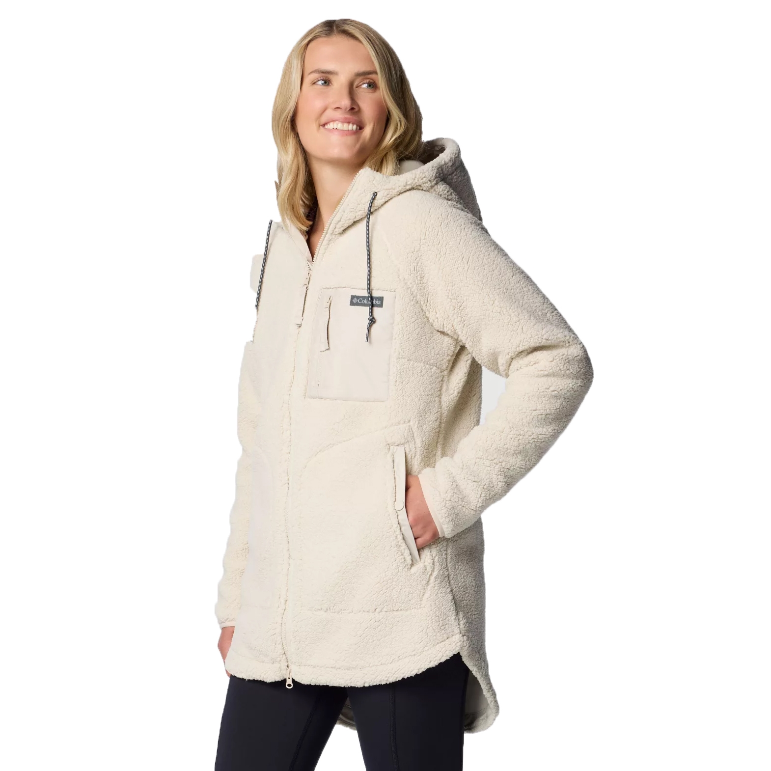 A woman models a Columbia Winter Warmth Jacket, which is a cozy, cream-colored, sherpa fleece with a hood, zip front, and drawstring ties. It features pockets at the front and chest for added convenience.