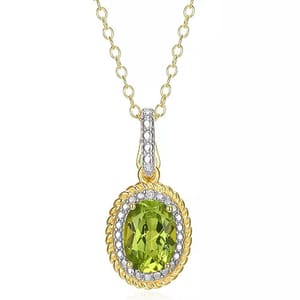A necklace with a green oval gemstone pendant set in gold, featuring a decorative border embellished with smaller clear stones. The pendant hangs from a gold chain.
