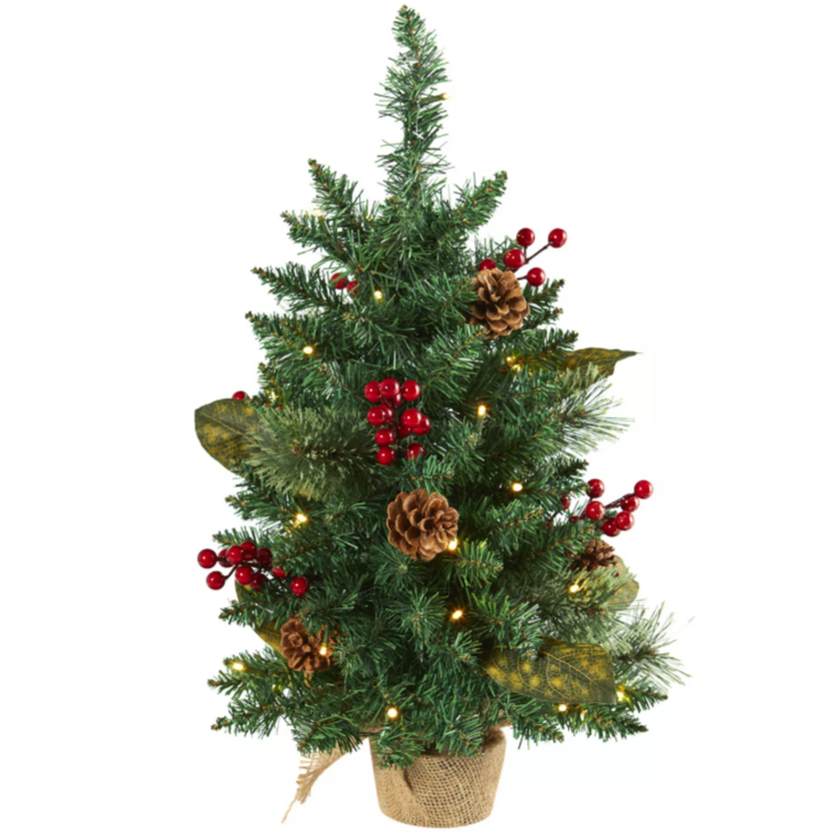 A small artificial Christmas tree decorated with red berries, pinecones, and warm white string lights, set in a burlap-wrapped pot.