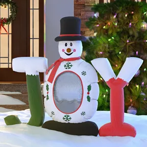 Inflatable decoration shaped like a snowman with a top hat and the letters \“JOY\“ on either side, set in a snowy holiday scene with Christmas lights.