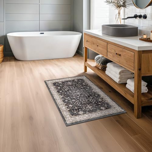 A bathroom features a freestanding bathtub, wooden vanity with a vessel sink, and a decorative rug with a floral pattern on light wood flooring.