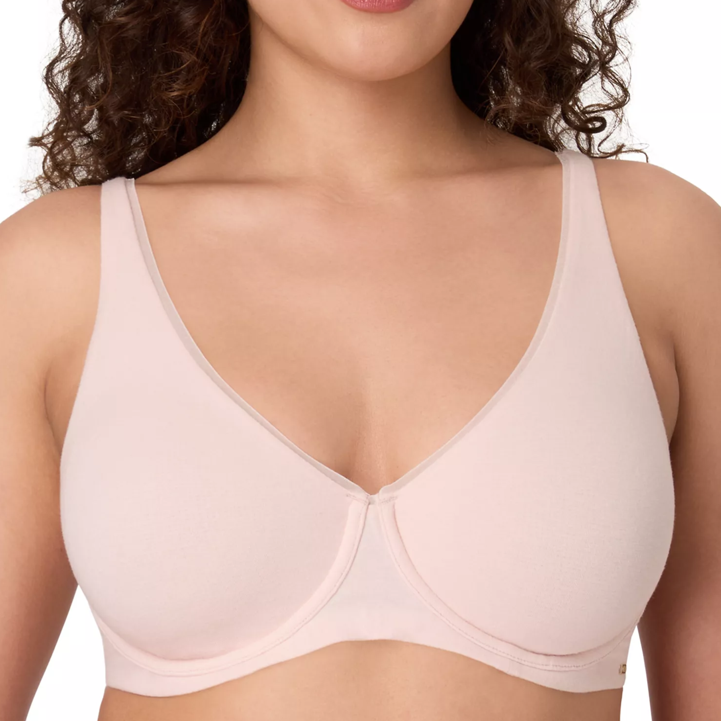 A woman is wearing a light pink, underwire bra with a smooth, seamless design and wide shoulder straps.