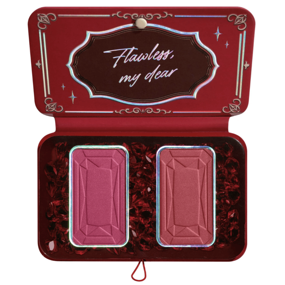 A red makeup palette opens to reveal two rectangular blush pans, encased in a decorative package with the phrase \“Flawless, my dear\“ on the inner lid.