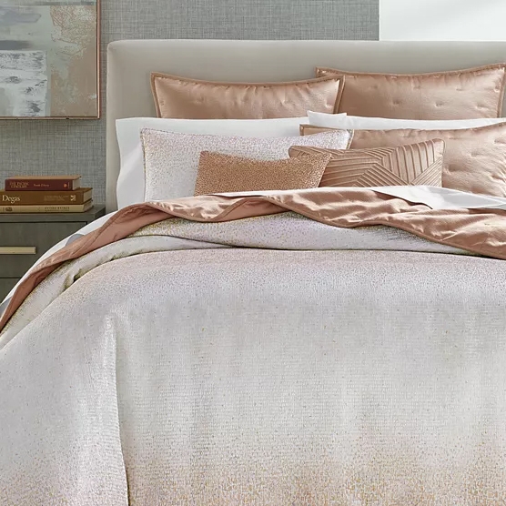 Luxurious duvet set featuring a soft, shimmering champagne color with a cotton-blend fabric. Includes multiple pillows with varying textures and a coordinating throw, creating an elegant and cozy bedroom setup.