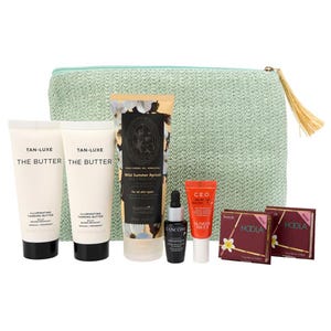 A collection of beauty products including self-tanning lotions, a serum, and bronzers, housed in a light green cosmetic bag with a tassel.