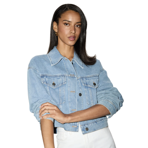 A woman is wearing a light blue denim jacket and white pants.