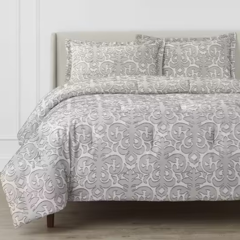 Gray and white patterned bedding set including a duvet cover and pillowcases on a bed.