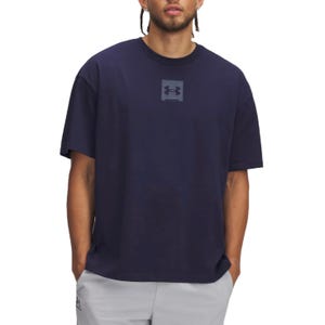 A man is wearing a navy blue Under Armour T-shirt featuring the brand's logo in the center. He is also wearing light gray shorts.