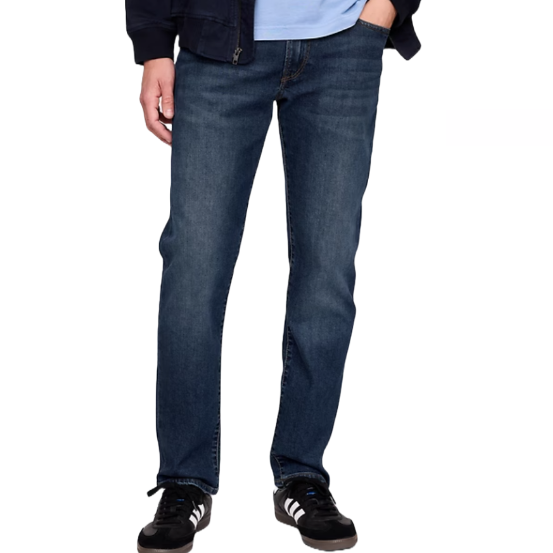 Men's straight fit jeans in medium dark wash, featuring a classic five-pocket style and paired with black and white athletic shoes.