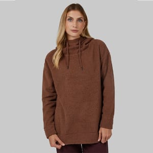 A woman wears a brown sherpa hoodie with long sleeves and a hood with drawstrings.