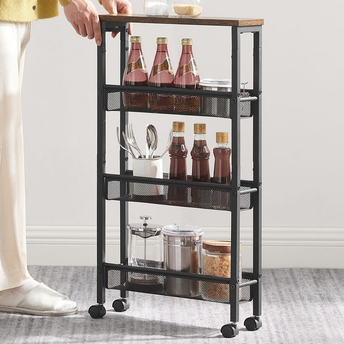 A compact rolling storage cart featuring three-tiered mesh shelves, containing bottles, spices, utensils in a container, and jars, ideal for kitchen organization. It has a metal frame, a wooden top, and four wheels for easy mobility.