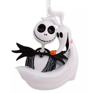 A Halloween-themed ornament featuring a skeleton with a stitched smile, wearing a black suit, and a ghost-like figure with a pumpkin nose, likely from a popular animated film.