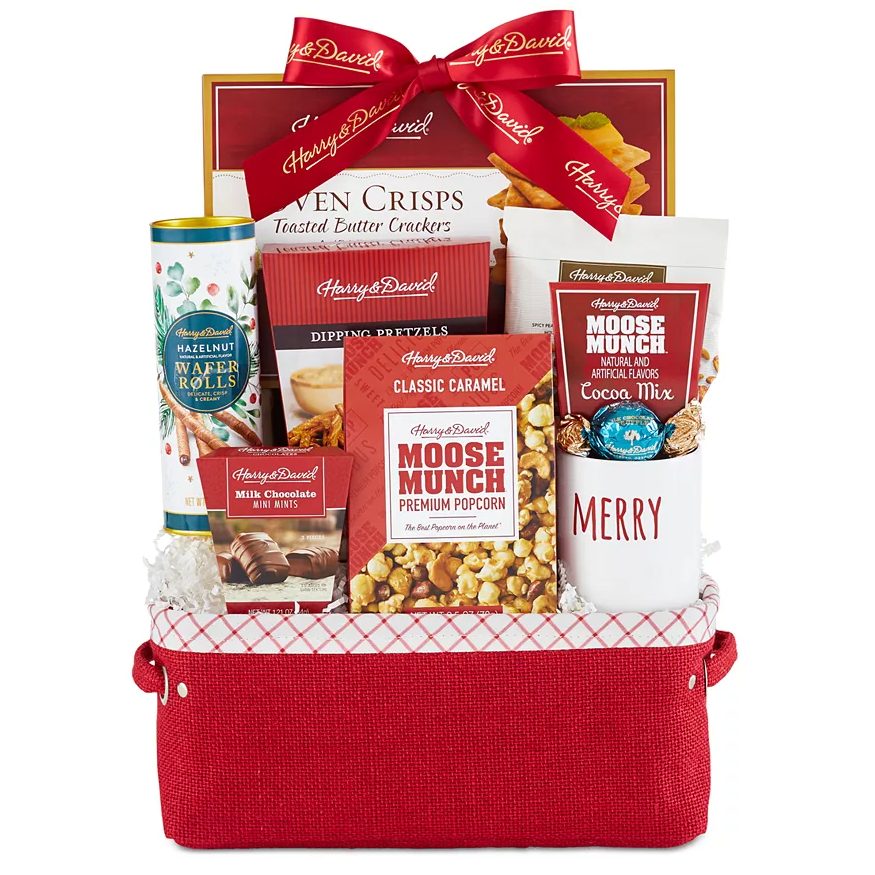 The Harry & David Moose Munch Gift Basket contains classic caramel Moose Munch popcorn, cocoa mix, toasted butter crackers, hazelnut wafer rolls, milk chocolate mini minis, and dipping pretzels, all wrapped in a decorative red basket with a ribbon.