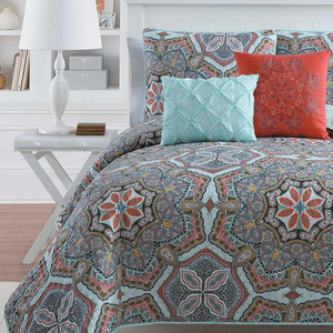 A patterned bedspread with coordinated pillows in teal, orange, and brown tones.