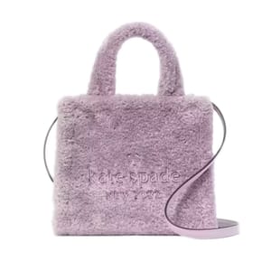 A lavender faux-fur tote with top handles and a shoulder strap, featuring \“kate spade new york\“ embossed on the front.