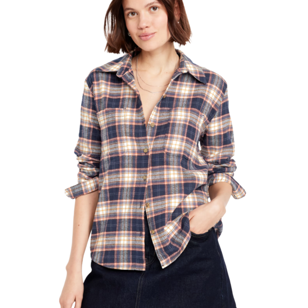 A woman is wearing a plaid flannel shirt with rolled-up sleeves and a dark skirt.