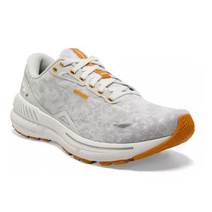 A single white and grey running shoe with orange accents and laces.