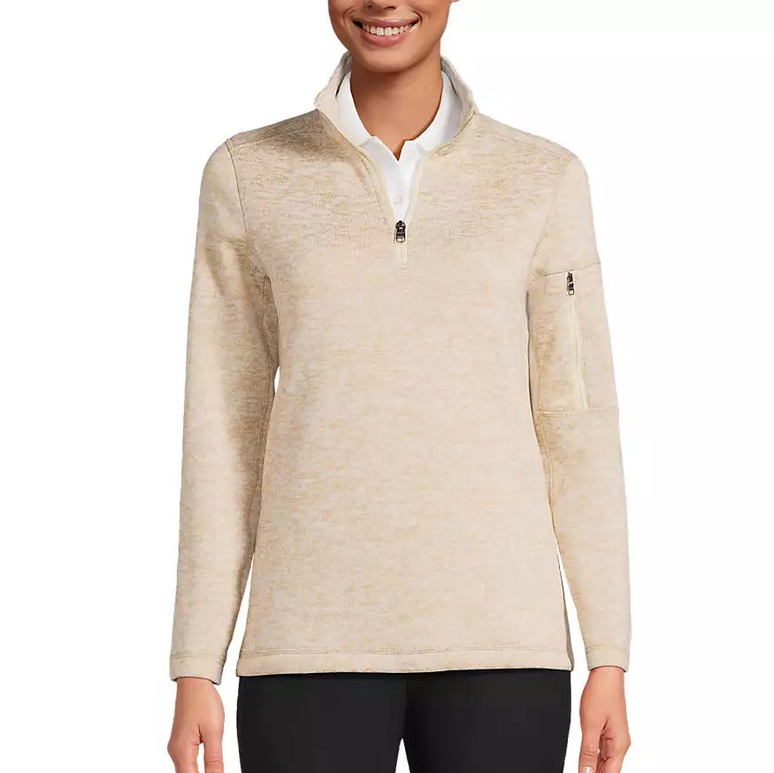 A light beige quarter-zip pullover with long sleeves featuring a zippered pocket on the left arm, paired with black pants.