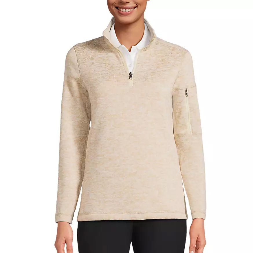 A light beige quarter-zip pullover with long sleeves featuring a zippered pocket on the left arm, paired with black pants.
