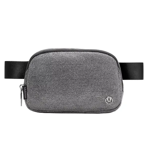 A gray crossbody belt bag with a textured fabric, featuring a zipper closure and an adjustable black strap. It has a small metal logo on the front.