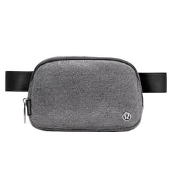A gray crossbody belt bag with a textured fabric, featuring a zipper closure and an adjustable black strap. It has a small metal logo on the front.