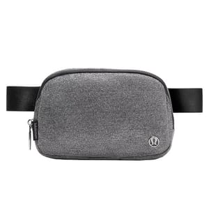 A gray crossbody belt bag with a textured fabric, featuring a zipper closure and an adjustable black strap. It has a small metal logo on the front.